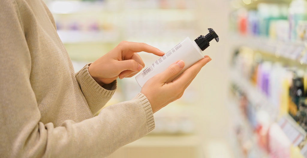 Woman checking batch number and expiry date on natural skincare products